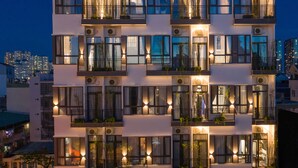 Ein mehrstöckiges Hotel mit Balkonen, Klimaanlagen und beleuchteten Fenstern.