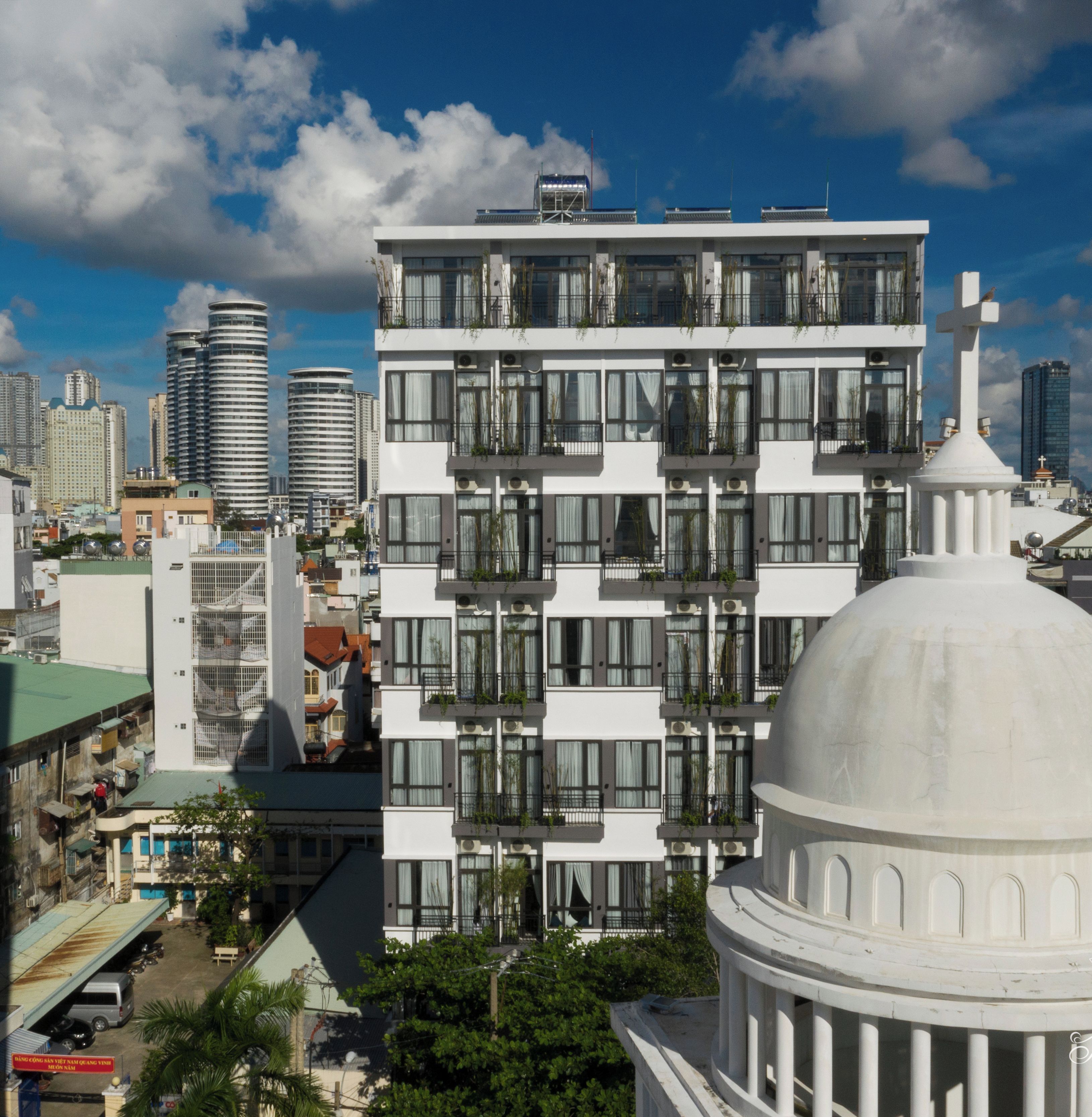 A modern multi-story building with balconies, large windows, and a dome structure in the foreground.