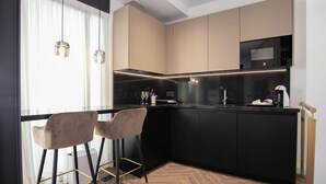 A modern kitchen with a black countertop, two bar stools, and a herringbone wood floor.