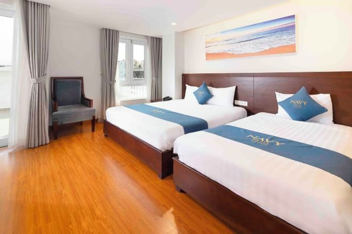 A hotel room with two beds, a TV, and a large window.