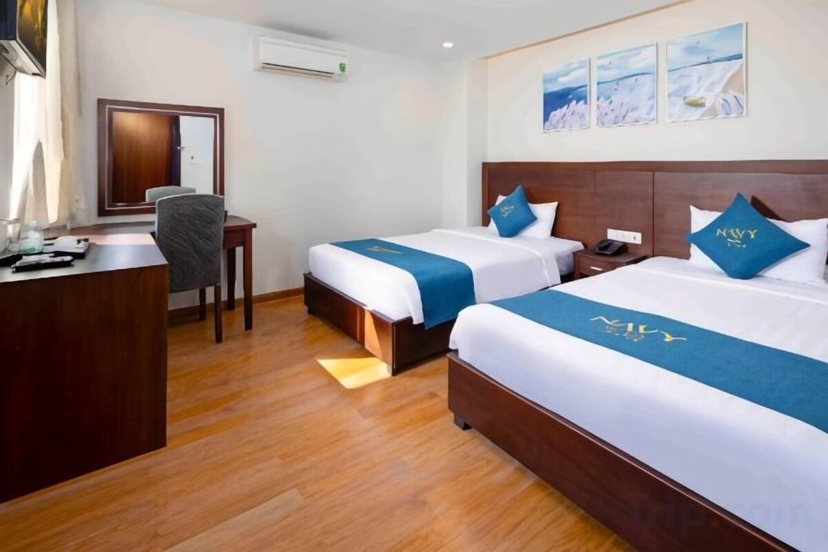 A hotel room with two beds, a desk, and a chair.