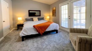 A bedroom with a bed, two bedside lamps, a mirror, a window with blinds, and a chair. - Spacious, FREE Private Heated Pool, Great Location! 10+ Guests & Pet Friendly (Mesa)