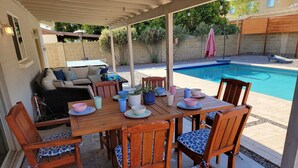 An outdoor patio with a wooden table and chairs, a pool, and a covered seating area. - Spacious, FREE Private Heated Pool, Great Location! 10+ Guests & Pet Friendly (Mesa)