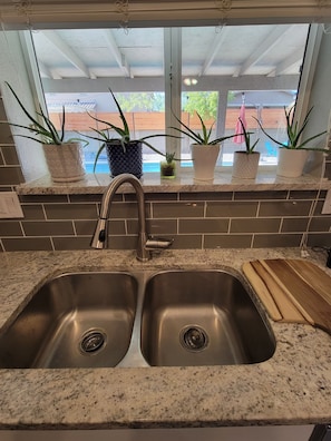 A kitchen with a double sink, granite countertop, and potted plants on the windowsill. - Spacious, FREE Private Heated Pool, Great Location! 10+ Guests & Pet Friendly (Mesa)