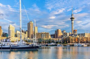 Een jachthaven met aangemeerde boten, een opvallende toren en een stadszicht met verschillende gebouwen.