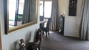 A spacious living room with a large mirror, a wooden rocking horse, a plush toy, a dining area with a table and chairs, and a wall-mounted key organizer.