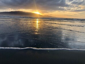 Une plage avec des vagues et un coucher de soleil.