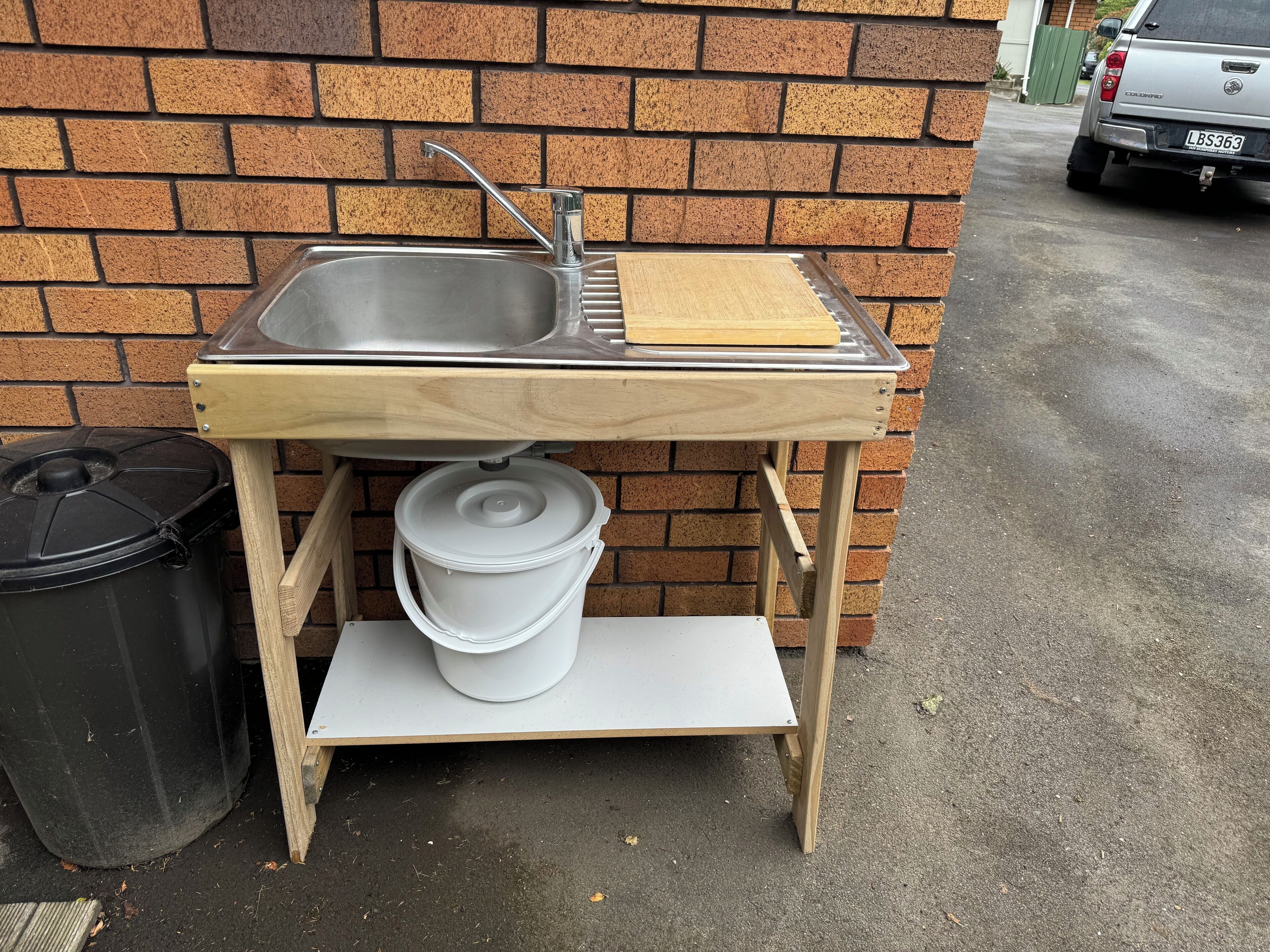 Un ensemble de cuisine portable comprenant un évier, une planche à découper et un seau.