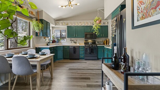 A modern kitchen with teal cabinets, a wooden dining table, and hanging plants. - *Home Gym* A/C* Fenced-in Yard (Flagstaff)