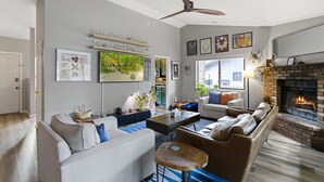 A modern living room with a fireplace, a ceiling fan, and a large window. - *Home Gym* A/C* Fenced-in Yard (Flagstaff)
