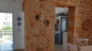 Ruime kamer met een stenen muur, houten plafond en een eethoek met tafel en stoelen.