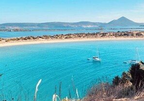 A coastal view with clear turquoise waters, a sandy beach, and boats. - Old fisher house (Marathopoli)