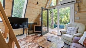 A cozy cabin interior with a large TV, leather sofa, and a wooden dining table.