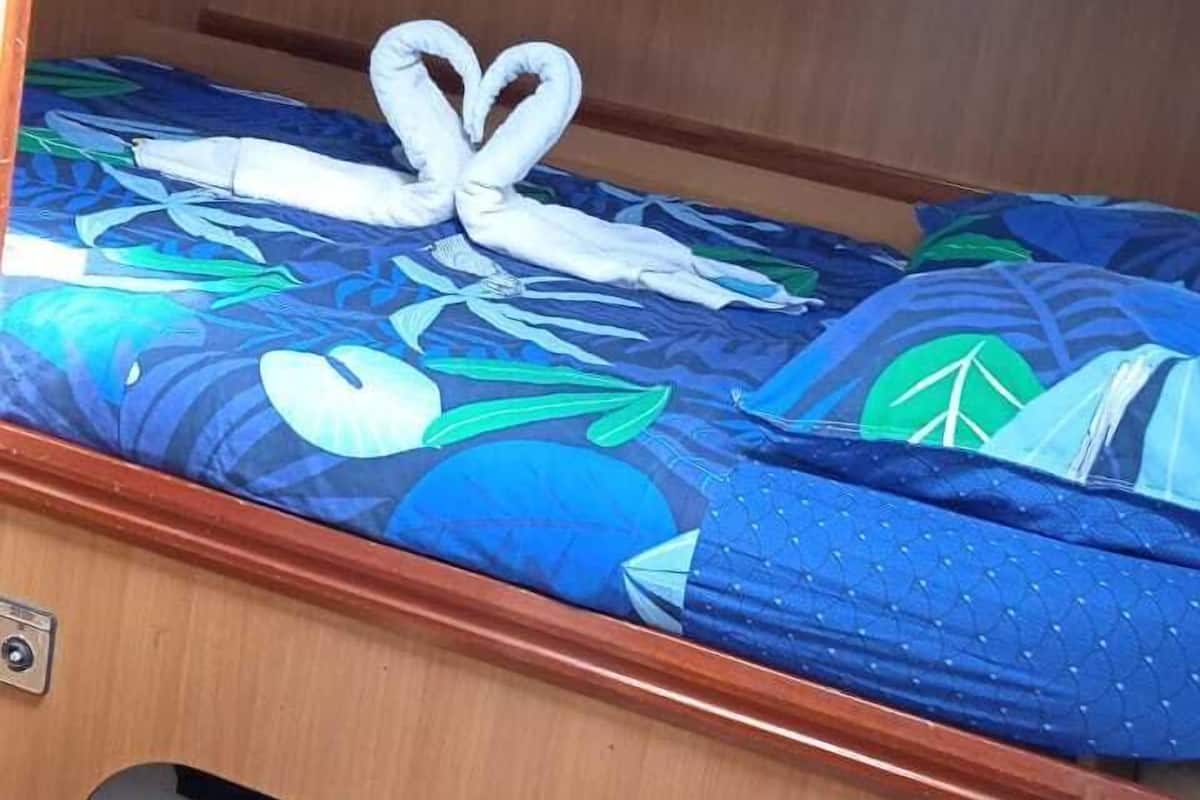 Una cama litera con una colcha azul estampada con flores y una almohada con forma de corazón blanco.