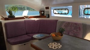 Ein gemütliches Interieur mit einer violetten gepolsterten Bank, einem kleinen Tisch mit Obstschale und einem dekorativen Gegenstand.