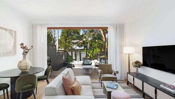 A modern living room with a sofa, chairs, a dining table, and a TV. - Charming Tropical Bondi Retreat (Bondi Beach)