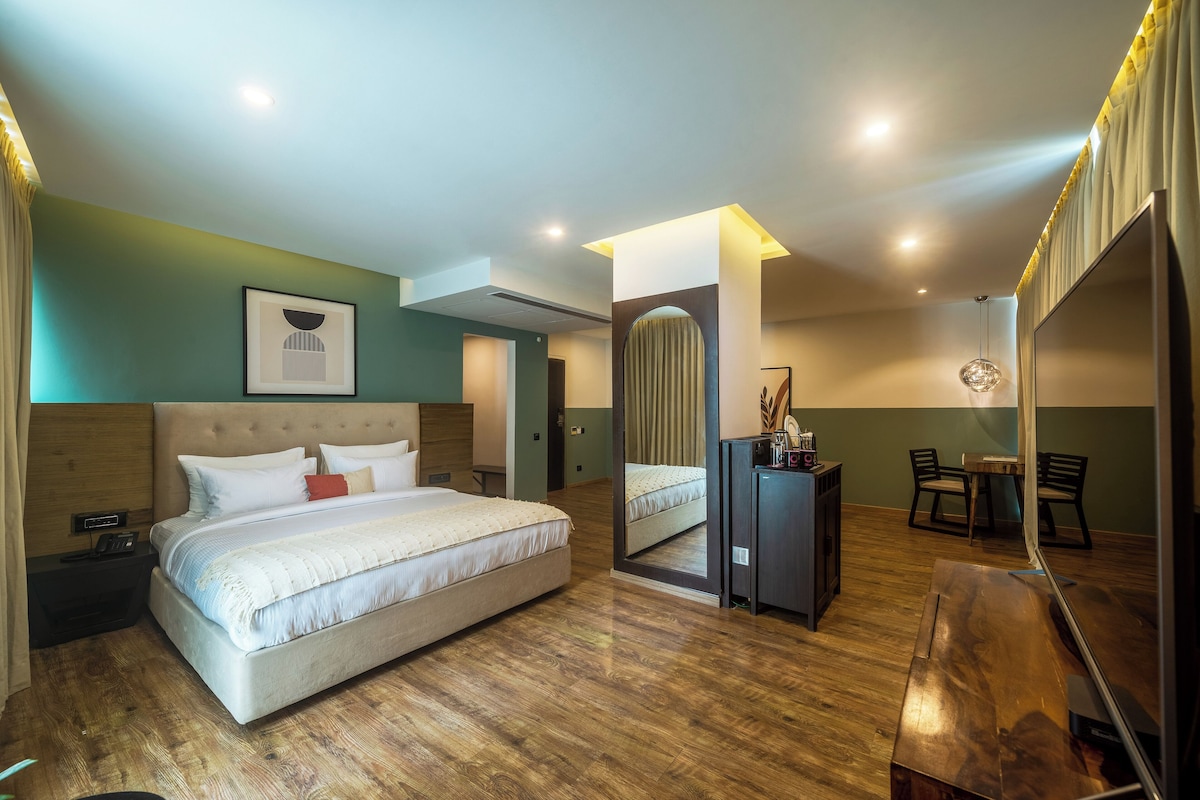 A modern hotel room with a large bed, a desk, and a mirror.