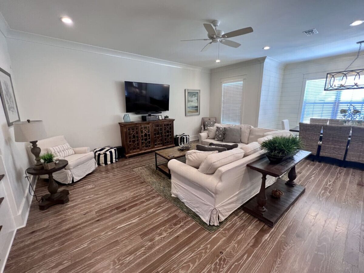 A spacious living room with a flat-screen TV, two sofas, a coffee table, and a ceiling fan.