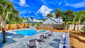 A backyard with a swimming pool, lounge chairs, and a wooden fence. - Private Beach Access|Golf Cart|Pool|Spa|Bikes (Rosemary Beach)