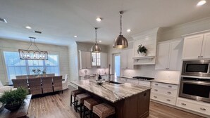 A modern kitchen with a central island, white cabinetry, and stainless steel appliances. - Private Beach Access|Golf Cart|Pool|Spa|Bikes (Rosemary Beach)