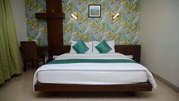 A neatly made bed with a green and white bedspread, two green pillows, and a framed picture on the wall above.
