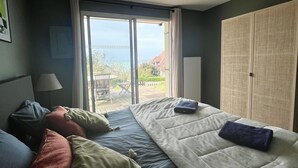 Un dormitorio con cama, almohadas, una lámpara y vistas al exterior.