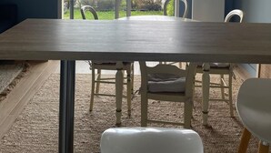 Un comedor con una mesa grande, sillas y vistas a un jardín a través de puertas de vidrio.