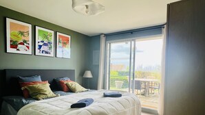 Un dormitorio con cama, vistas al exterior y obras de arte en la pared.