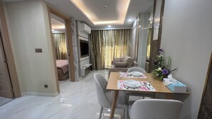 A modern hotel room with a dining area, a sofa, and a TV.