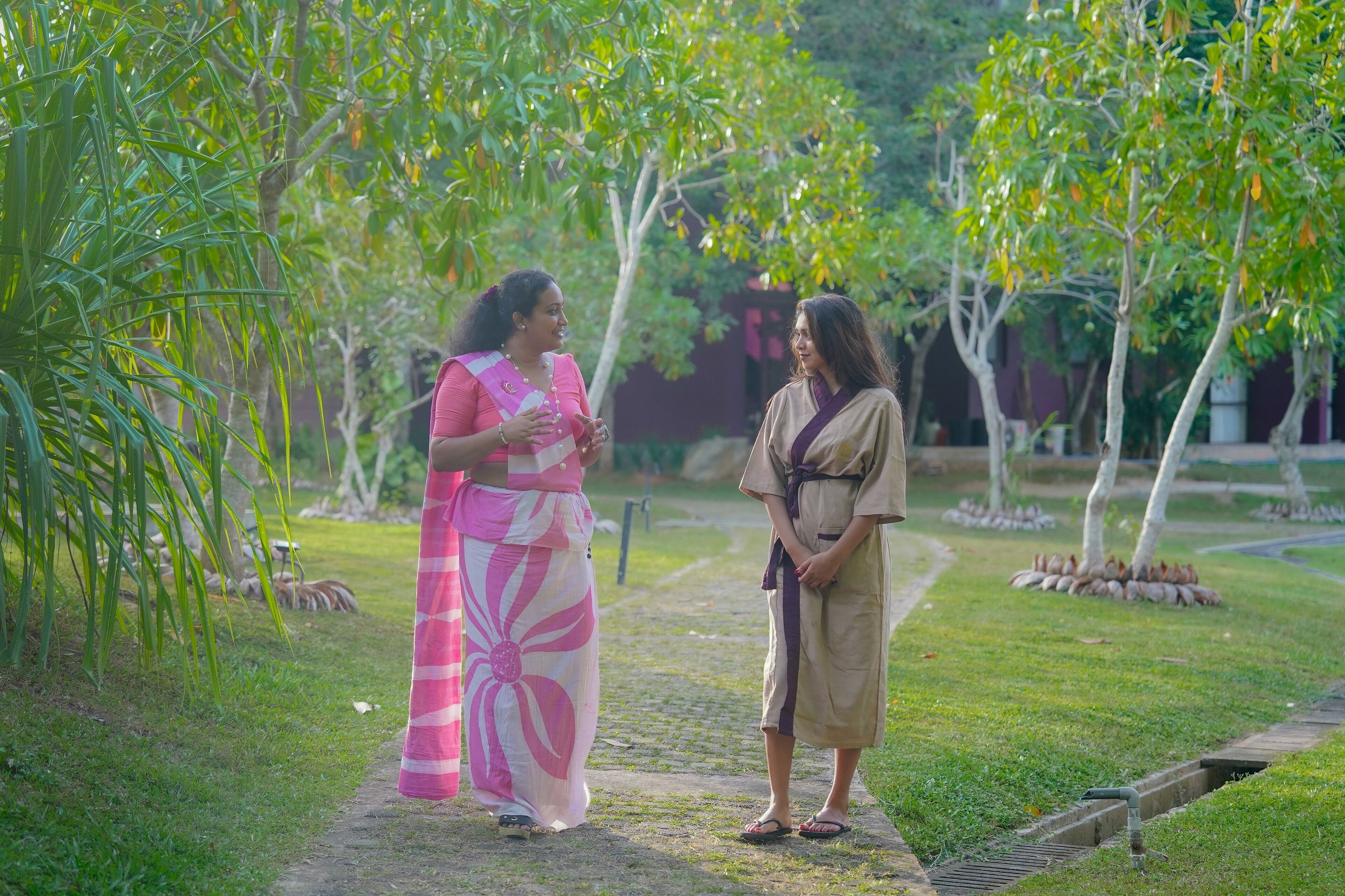 Two people standing on a pathway surrounded by greenery.