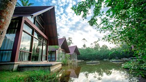 A modern building with large windows and a reflective water body in front.
