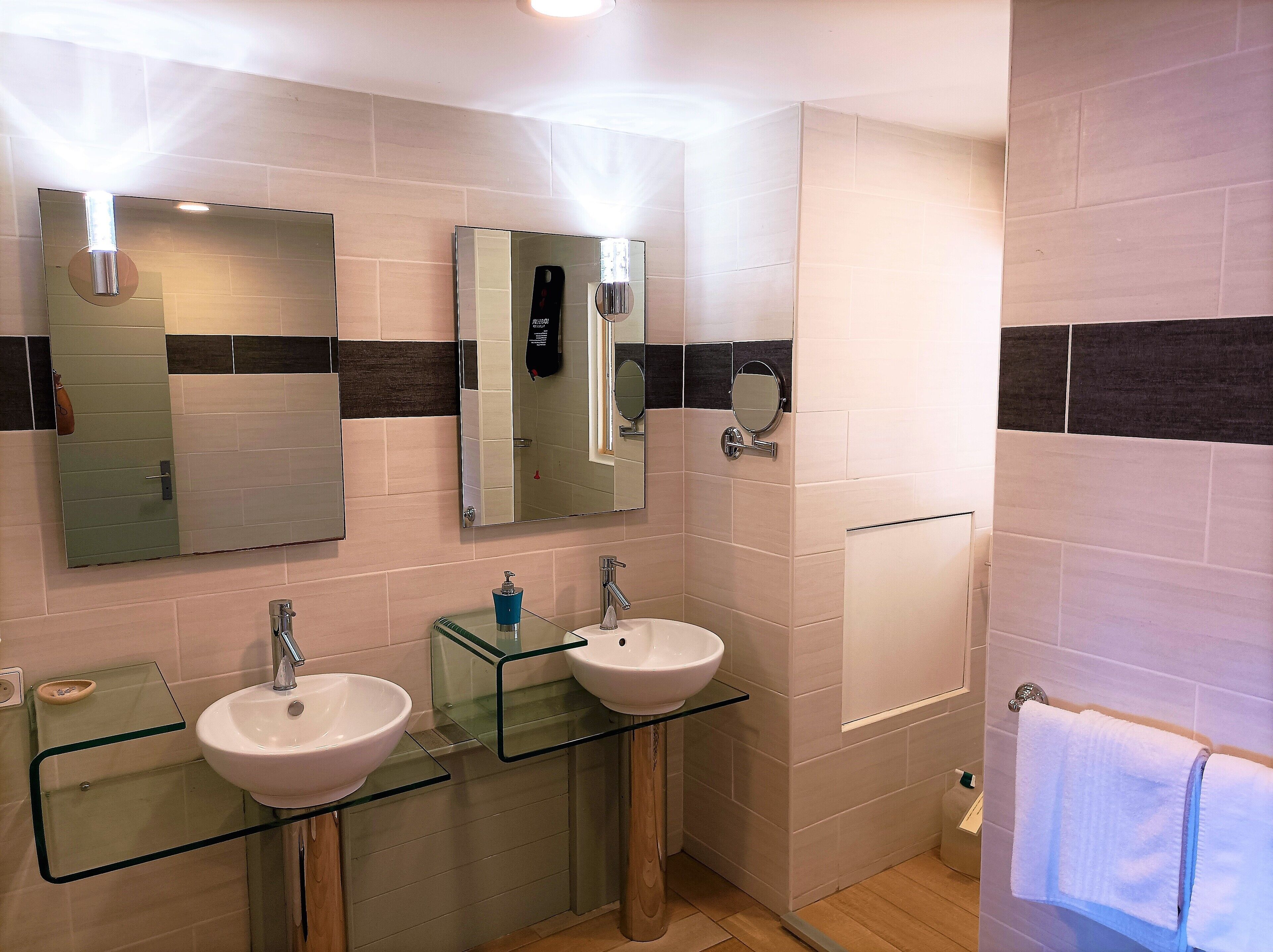 Ein modernes Badezimmer mit zwei Waschbecken, einem großen Spiegel und einem Handtuchhalter.
