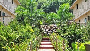 A wooden staircase surrounded by lush greenery leading to a stone structure. - Hôtel Hamaha Beach (Mamoudzou)