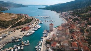 An aerial view of a coastal town with a marina, a prominent tower, and surrounding hills. - Holiday House O'Live - private house with a garden few steps from the sea (Marina)