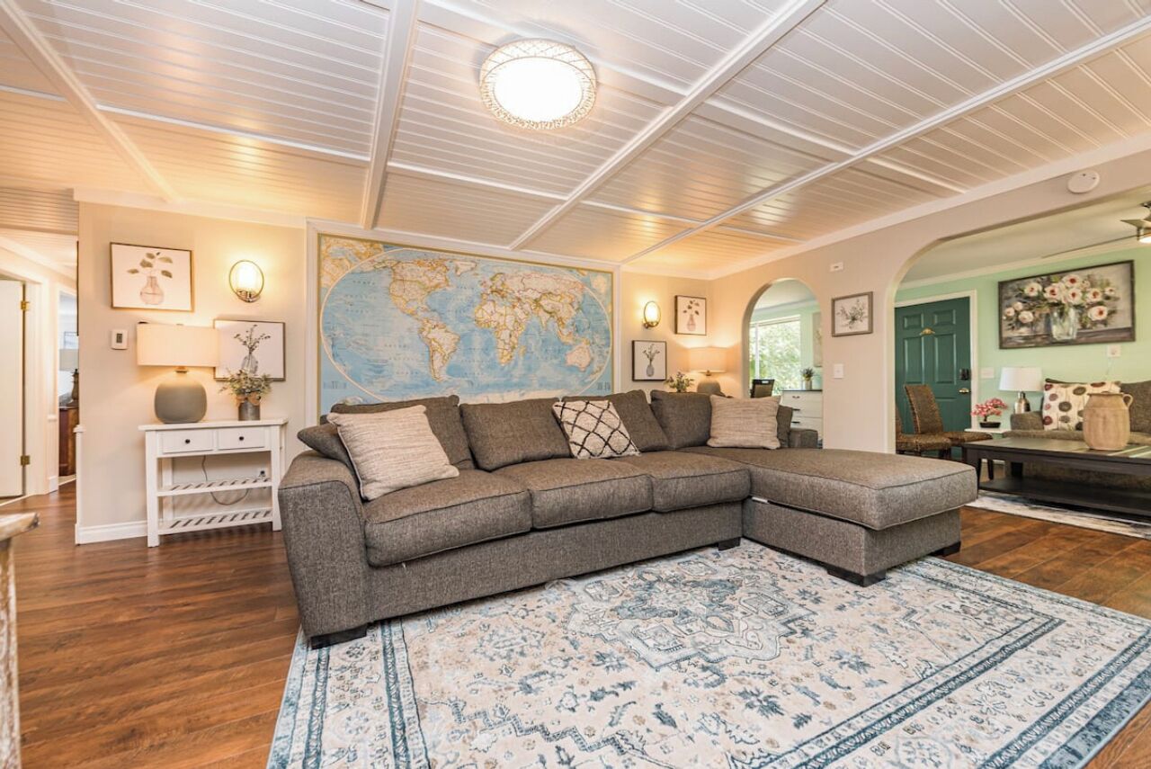 A living room with a sectional sofa, a world map on the wall, and a patterned rug.