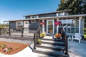A modern two-story house with a covered porch, a small deck, and a front door with a wreath.