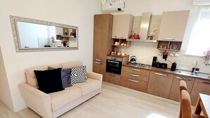 A modern kitchen with a dining area, a sofa, and a chandelier.