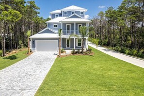 A two-story house with a garage, surrounded by a well-maintained lawn and trees.