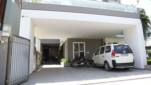 Un bâtiment moderne doté d’un parking couvert, avec un fourgon blanc et une moto garés devant.
