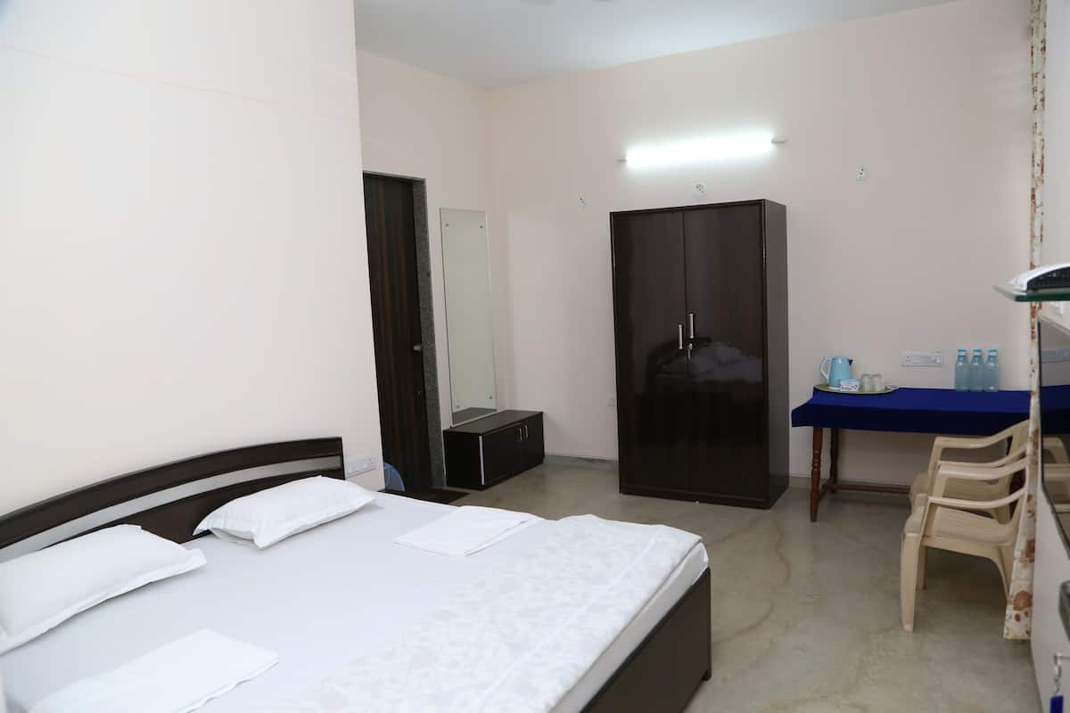 A hotel room with a bed, a wardrobe, a desk with a chair, and a mirror.