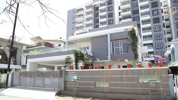 Un immeuble résidentiel à plusieurs étages, doté de balcons, d’une entrée sécurisée et de plantes en pot.