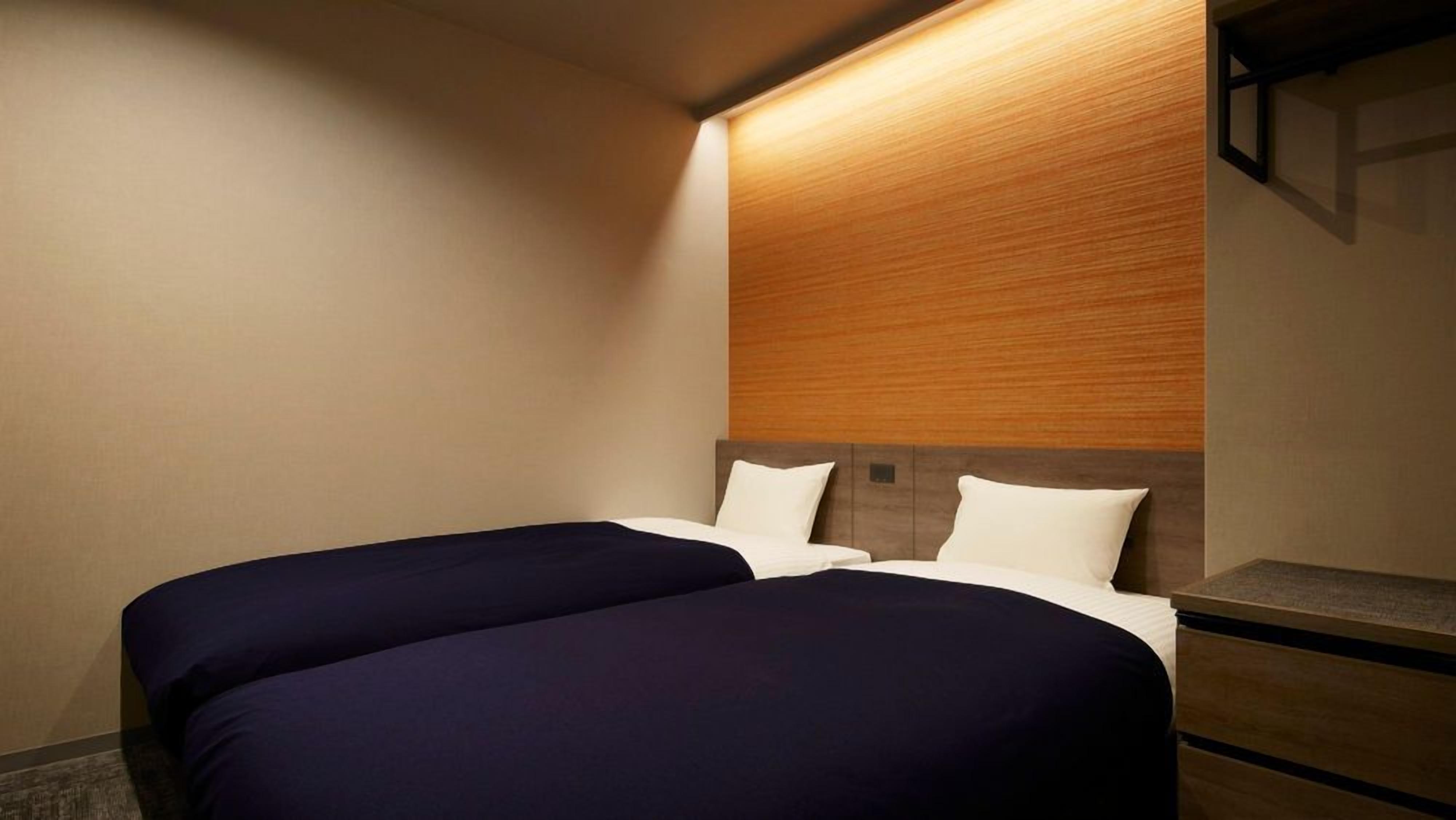 Ein Hotelzimmer mit zwei Betten, einem Holzkopfteil und einem Nachttisch.