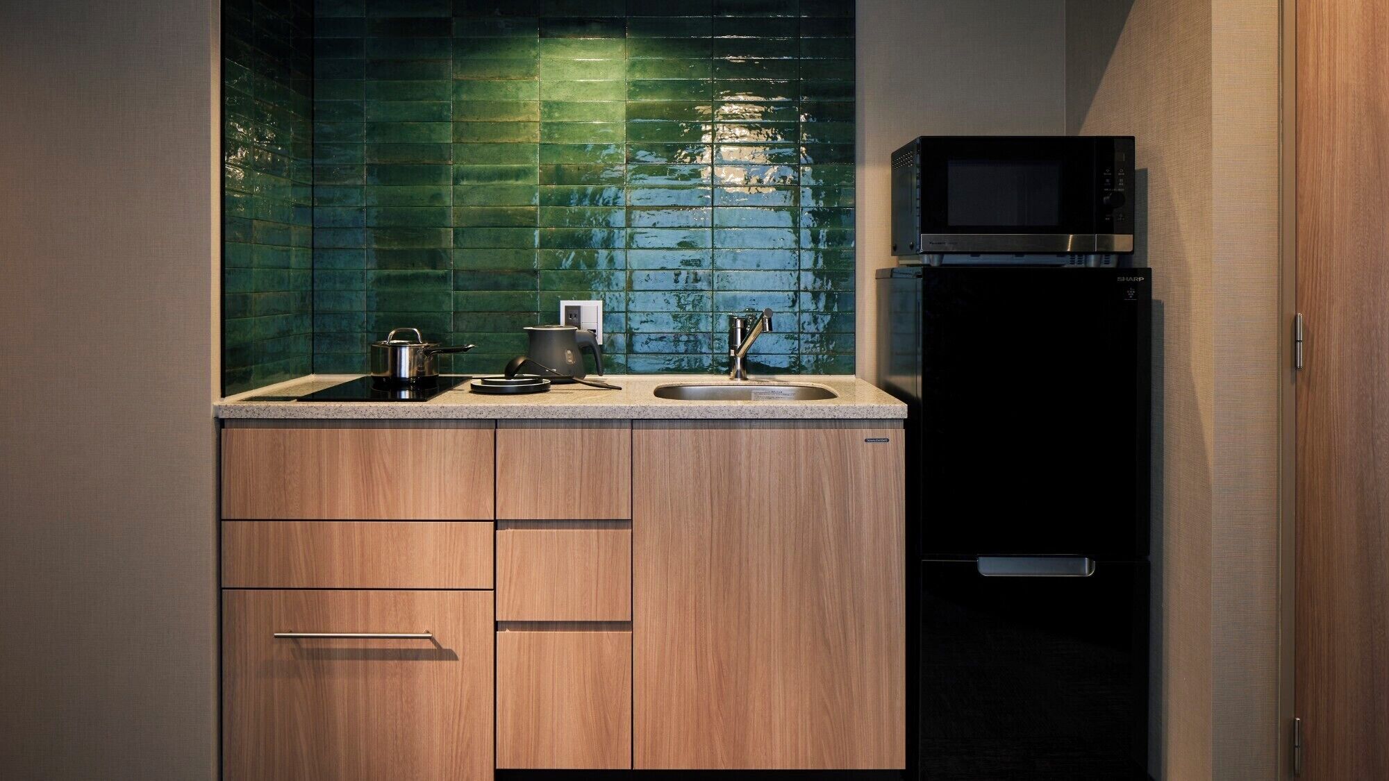 A modern kitchen with a black refrigerator, a microwave, a sink, and wooden cabinets.