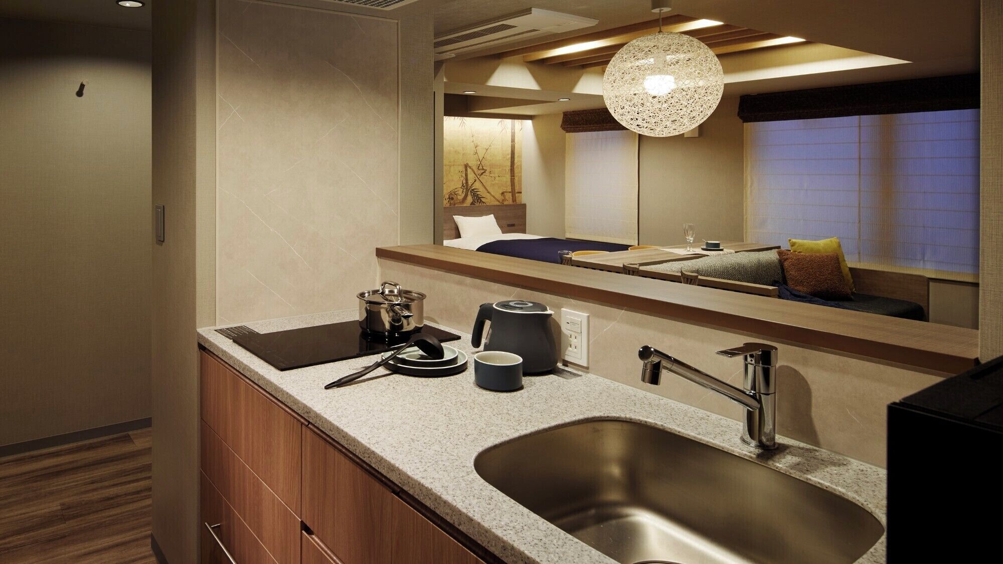 A modern bathroom with a large sink, a mirror, and a hanging light fixture.