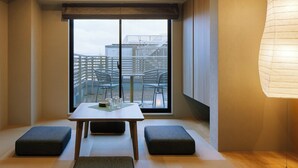 A modern room with a large window, a table with chairs, and two ottomans. - Minn Gion Sanjo (Kyoto)