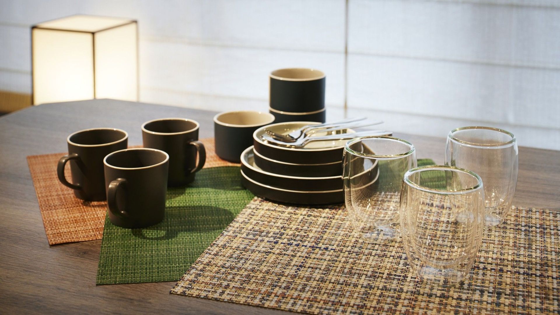 Une table dressée avec différents plats, notamment des assiettes, des bols et des tasses, disposés sur un set de table en fibres tressées.