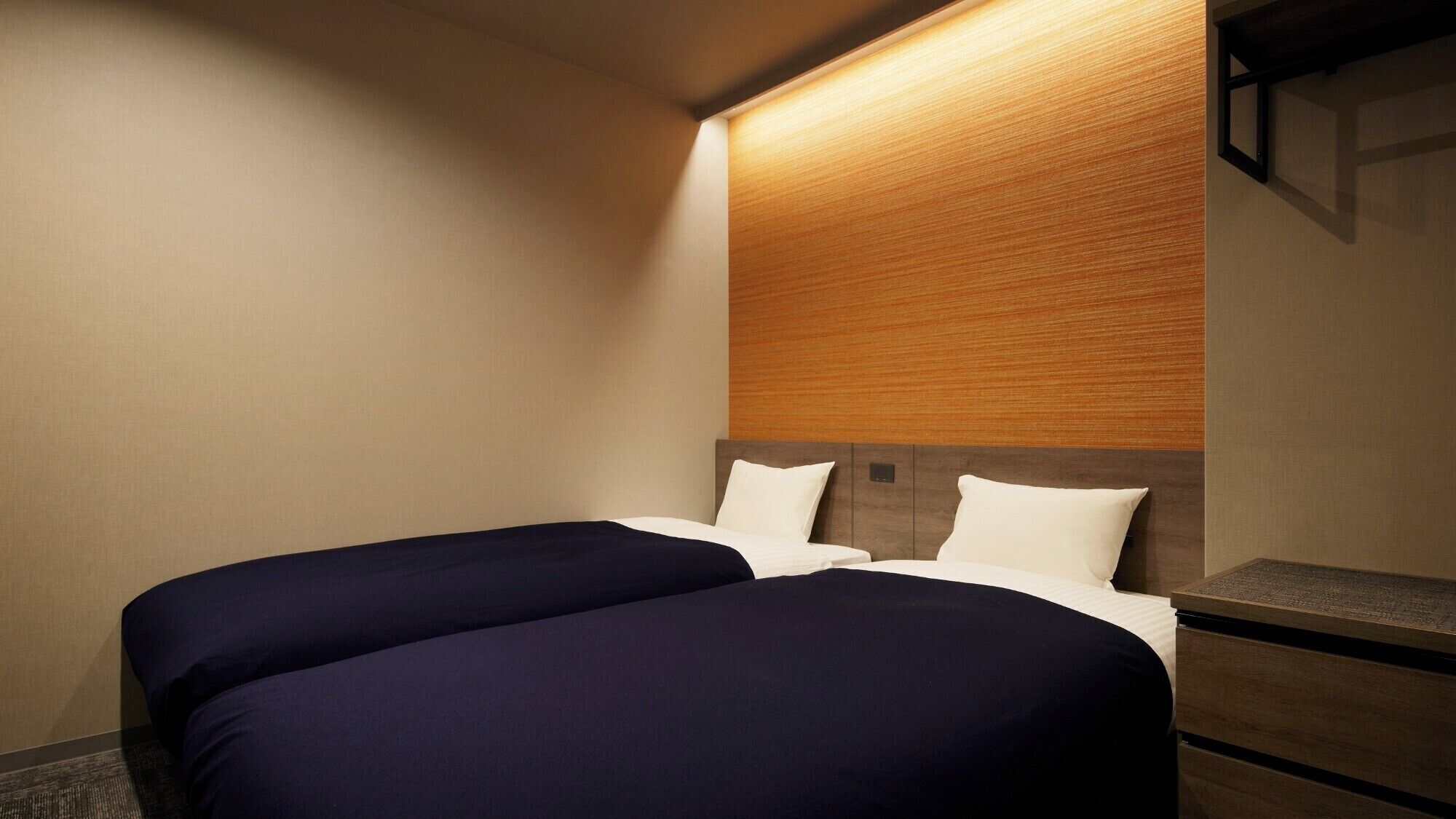 A hotel room with two beds, a wooden headboard, and a nightstand.