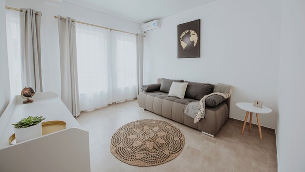 A modern living room with a sofa, a round woven rug, a globe on a table, and a world map on the wall. - THE NOOK APARTHOTEL  (Timisoara)