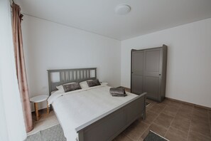 A bedroom with a bed, a wardrobe, a small table, and a curtain. - THE NOOK APARTHOTEL  (Timisoara)