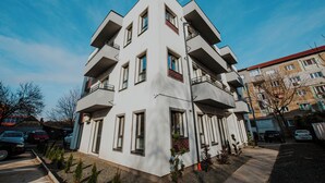 A modern multi-story building with balconies, a parking area, and a clear sky. - THE NOOK APARTHOTEL  (Timisoara)